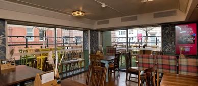 Cozy pub interior with wooden tables and large windows overlooking the street.