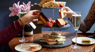 Two people enjoying an elegant afternoon tea with sandwiches and pastries.