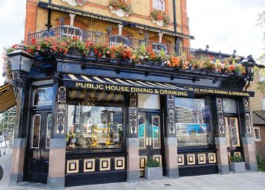 Traditional British pub with floral decorations and classic black and gold exterior.