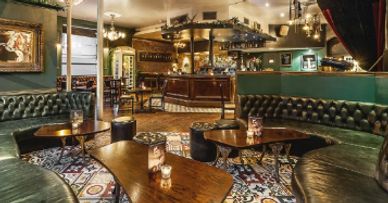 Cozy vintage-style pub interior with leather seating and wooden tables.