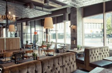 Cozy modern cafe interior with tufted sofas and large windows letting in natural light.