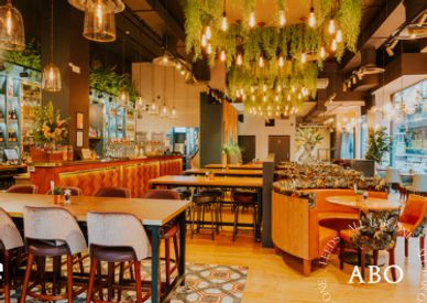 Cozy, modern restaurant interior with warm lighting and lush greenery.