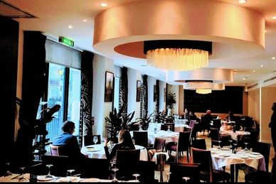 Elegant restaurant interior with modern lighting and neatly set tables.