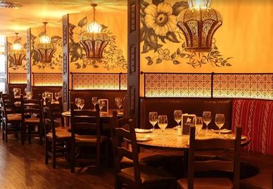 Cozy restaurant dining area with warm lighting and floral wall decor.