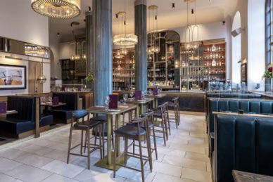 Elegant restaurant interior with bar seating and chandeliers.