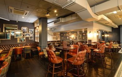 Cozy bar with leather chairs and framed photos on the walls.