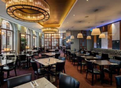 Elegant empty restaurant with modern lighting and marble tables.