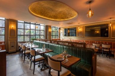 Elegant restaurant interior with green leather seating and warm lighting.