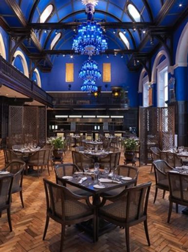 Elegant restaurant with blue chandeliers and arched windows.
