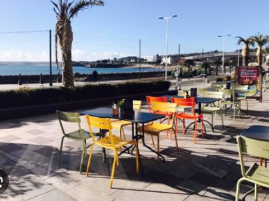 Colorful outdoor cafe seating by the seaside on a sunny day.