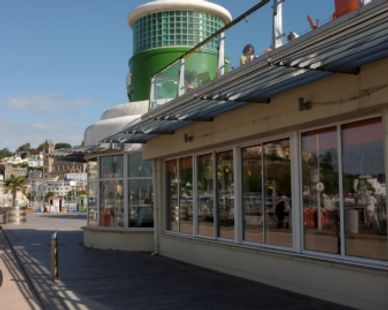 Harbor-side building with large windows and a green chimney under blue sky.