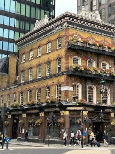 Historic brick building adorned with flowers on a city street corner.