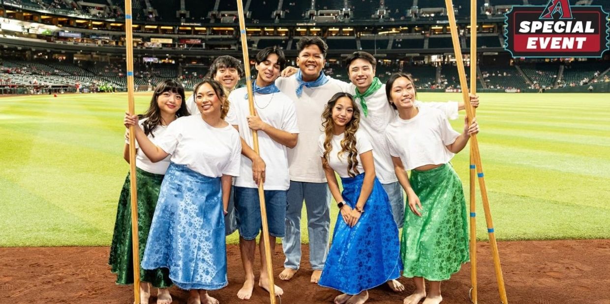 Group of young people in traditional attire posing on a baseball field during a special event.