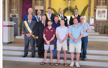 Group portrait of men in formal and casual attire inside a church.