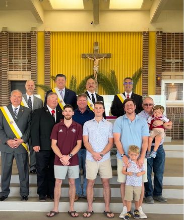 Group of men and children posing inside a church with a crucifix in the background.