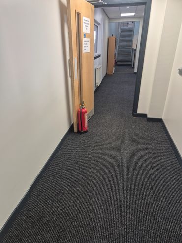 Office hallway with open door and fire extinguisher.
