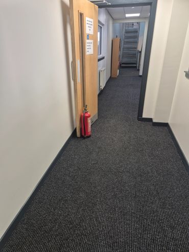 Office hallway with open door and fire extinguisher.