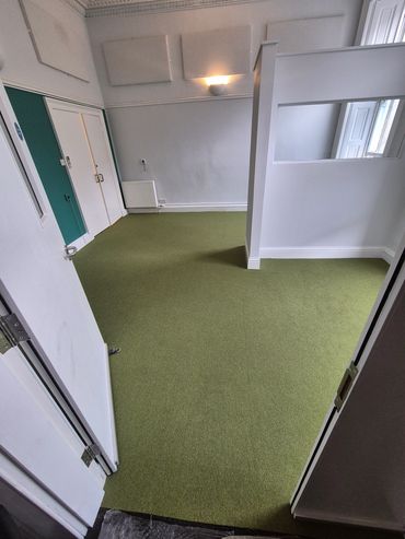 Empty room with green carpet and white walls.
