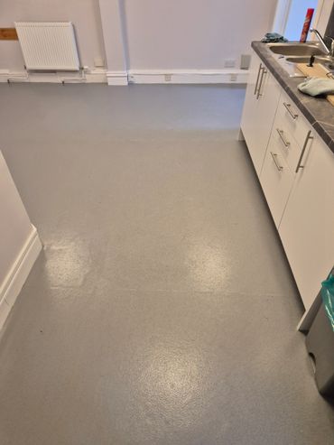 Clean kitchen floor with white cabinets and a sink.