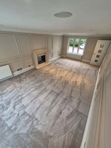 Spacious living room with fresh carpet and light beige walls.