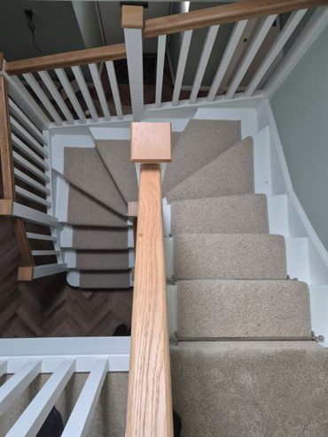 Carpeted staircase with wooden handrails and white banisters.