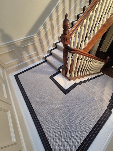Carpeted staircase with wooden banister and white panelled walls.
