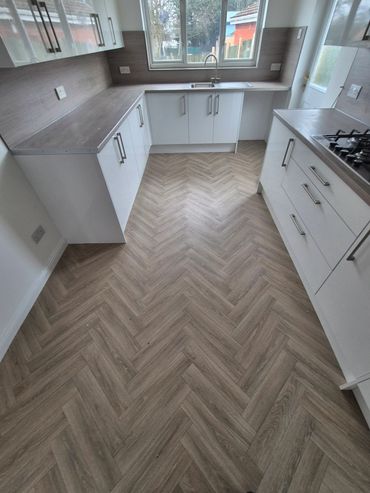 Modern kitchen with white cabinets and wood-patterned flooring.