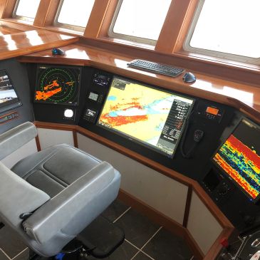 Ship control room with navigation screens and chair.