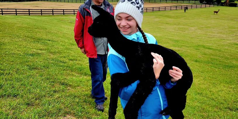 Girl holding a black alpaca cria at Skyfiber Ranch Alpacas