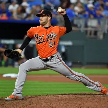 Baltimore Orioles pitcher in mid-throw during a baseball game.