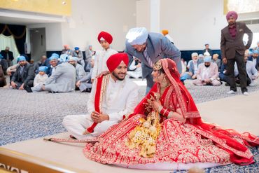 A Sikh couple in traditional wedding attire during a ceremony.