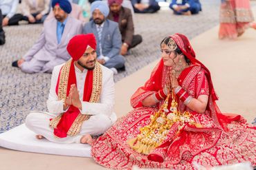 Indian Sikh bride and groom in traditional attire during wedding ceremony.