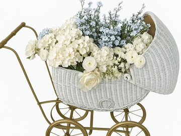 Vintage white wicker baby carriage filled with white and blue flowers.