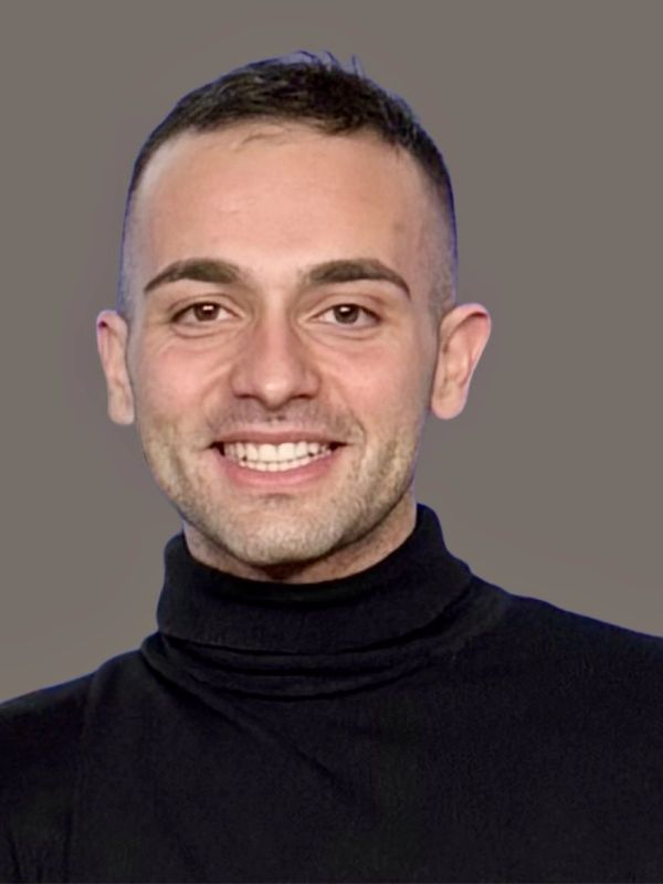 Smiling man in a black turtleneck against a plain background.