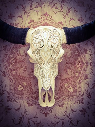 Rustic carved buffalo skull with ornate design and dark horn finish


