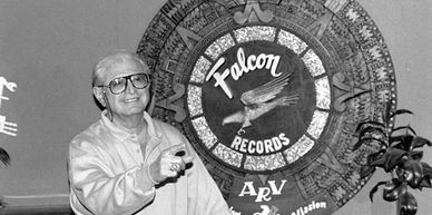 Elderly man posing near Falcon Records logo.