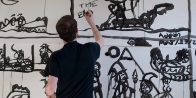 Man painting comic panels on a wall.