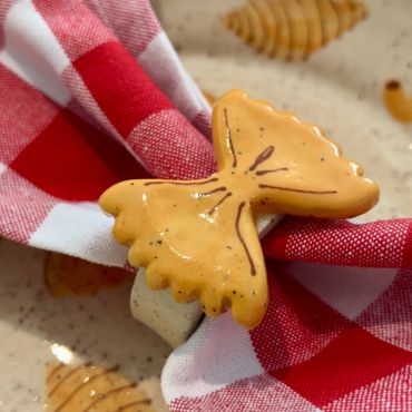 A detail shot of a hand made ceramic bow tie napkin ring on a checkered cloth.
