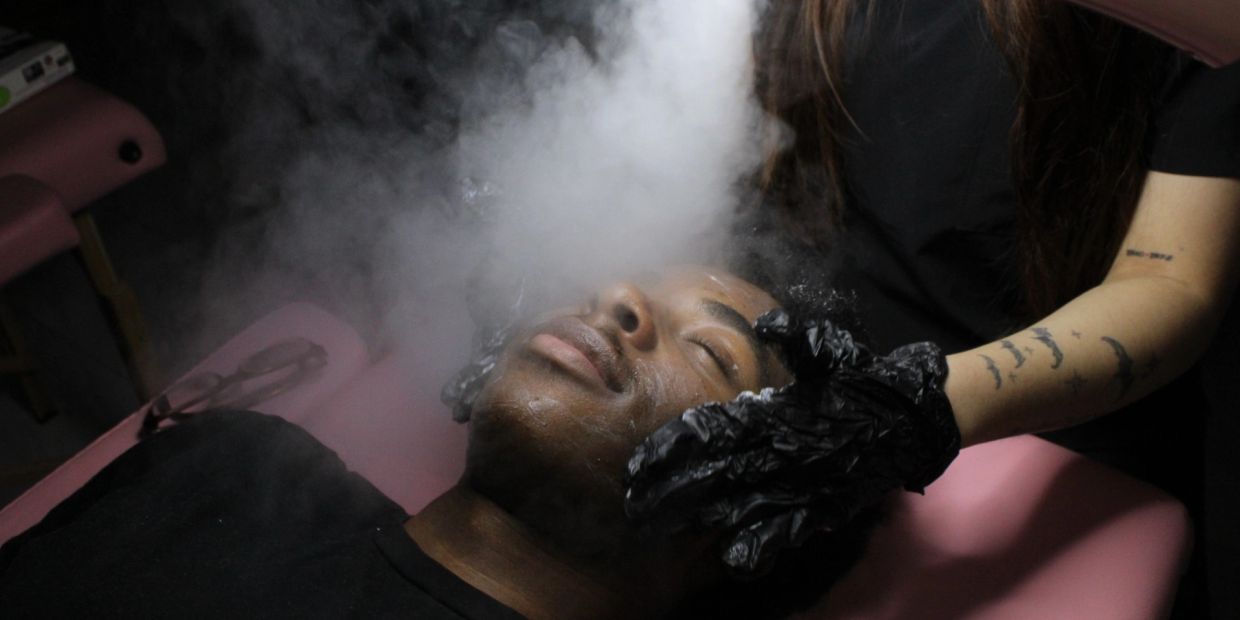 Man receiving facial steam treatment at spa.