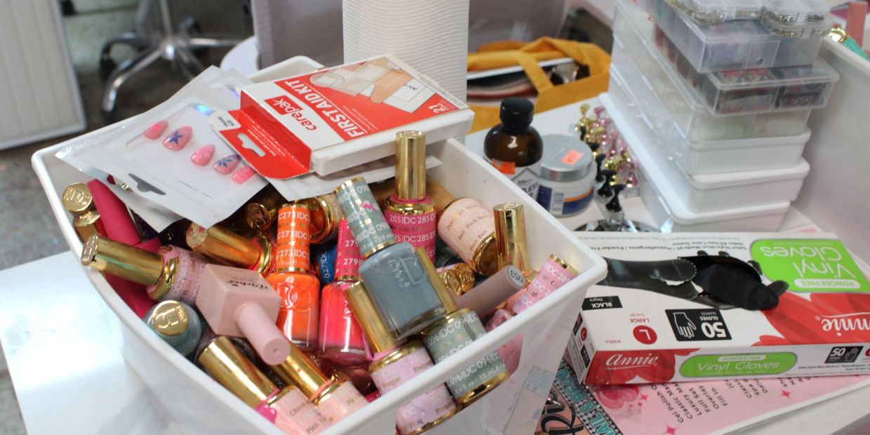 Box filled with various nail polish bottles and nail care items on a table.