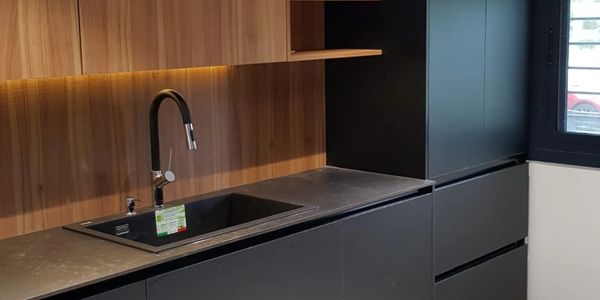 Cocina moderna con fregadero negro y muebles oscuros.