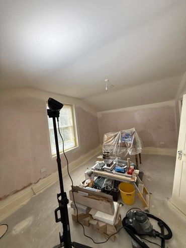 Room under renovation with tools and covered furniture.