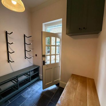 Minimalist entryway with a door, coat racks, and wooden bench.