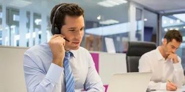 Man in headset talking at office desk.