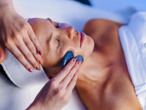 Woman receiving facial treatment with gua sha.