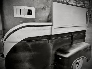 Black and white image of a vintage trailer with a small window.