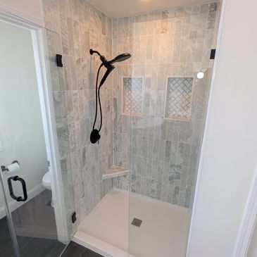 Modern shower with gray tiles and black fixtures.
