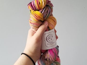 A dk skein of Rainbow Brite held in front of a grey background.