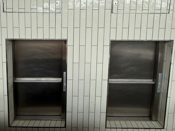 Commercial stainless steel food lifts installed in a modern hospitality kitchen, double dumbwaiter 
