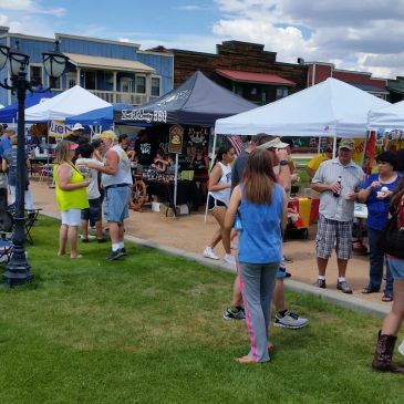 People enjoy a lively outdoor market with tents on a sunny day.